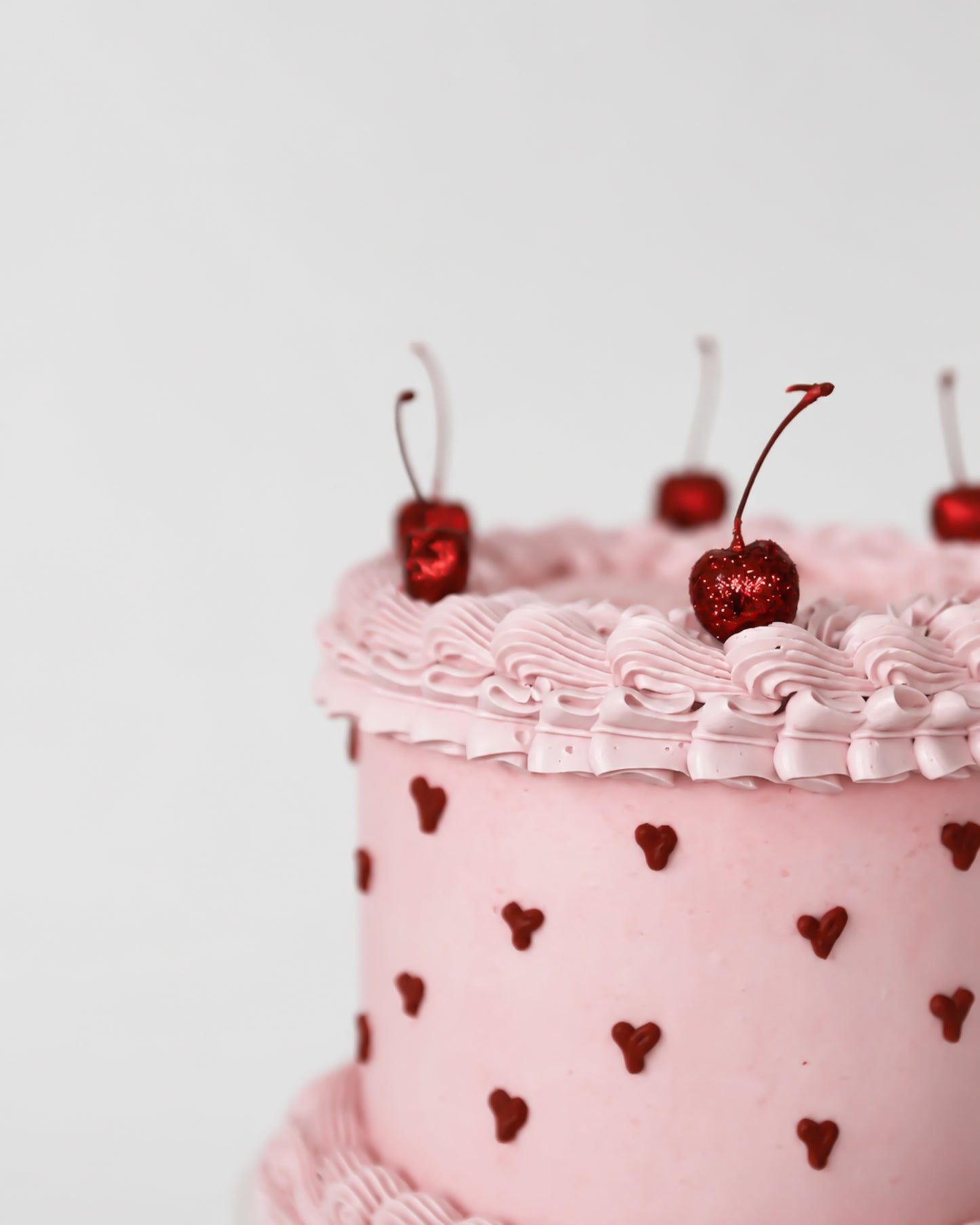 Close-up of blush pink buttercream cake with hand-piped dark red heart dot pattern