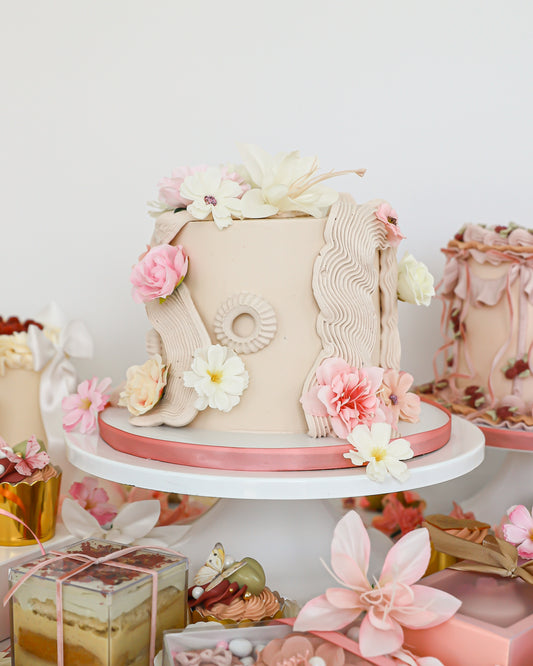 Floral Mother’s Day cake display with pastel desserts and gift boxes
