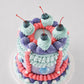 Ariel cake with lavender buttercream, chocolate seashells, coral ribbon stripes, and glitter cherry topper
