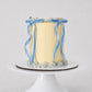 Bluebell Bow mini cake in soft yellow with pale blue shell piping and blue velvet ribbon bows