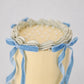 Top view of Bluebell Bow mini cake showing pearl dot sprinkles, shell piping border, and velvet bow