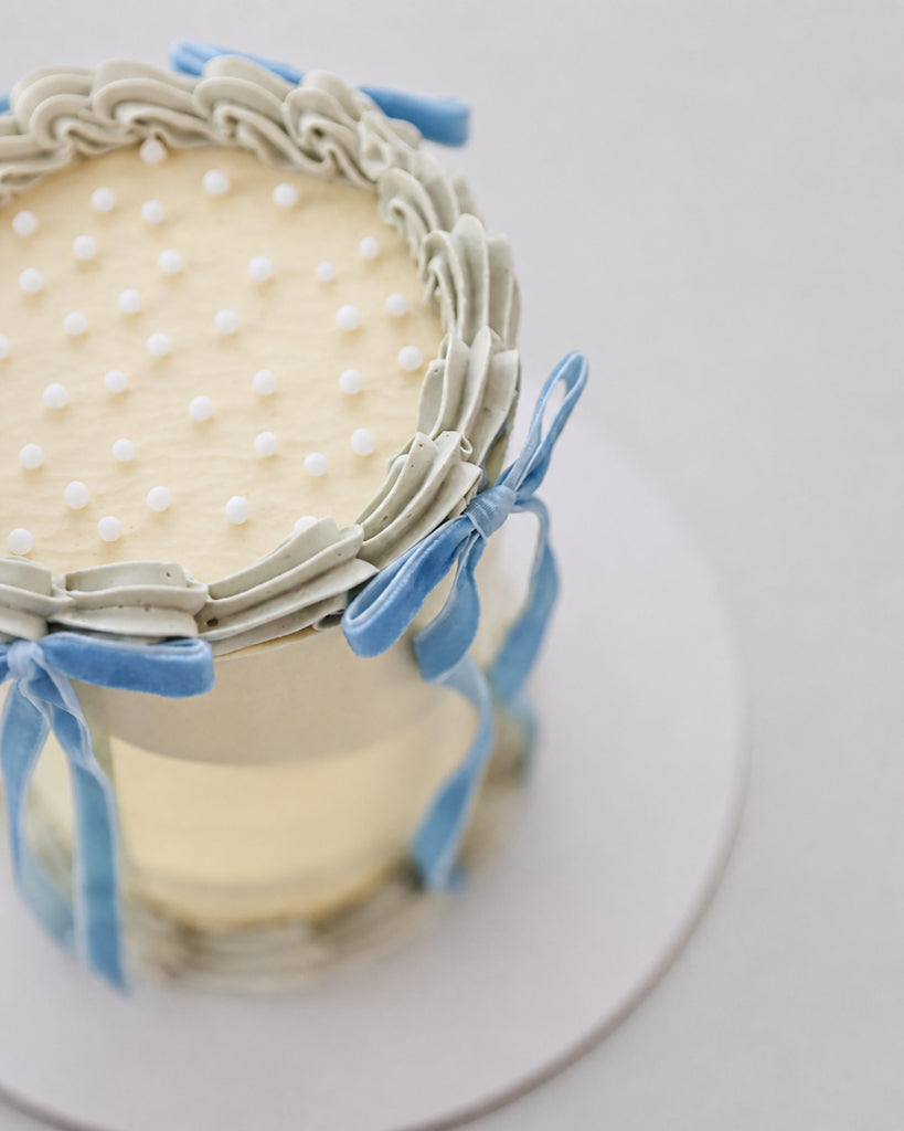 Close-up of a blue velvet ribbon bow on Bluebell Bow mini cake with ribbon trailing down the side