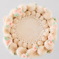 Top view of Charlotte cake showing a wreath of ruffled piping, beaded border, and pink roses with green leaves