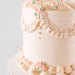 Close-up of Charlotte's beaded pearl garland with fringe tassel and piped pink roses