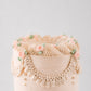 Charlotte cake detail showing ruffled scalloped border, beaded swag, and rose accents
