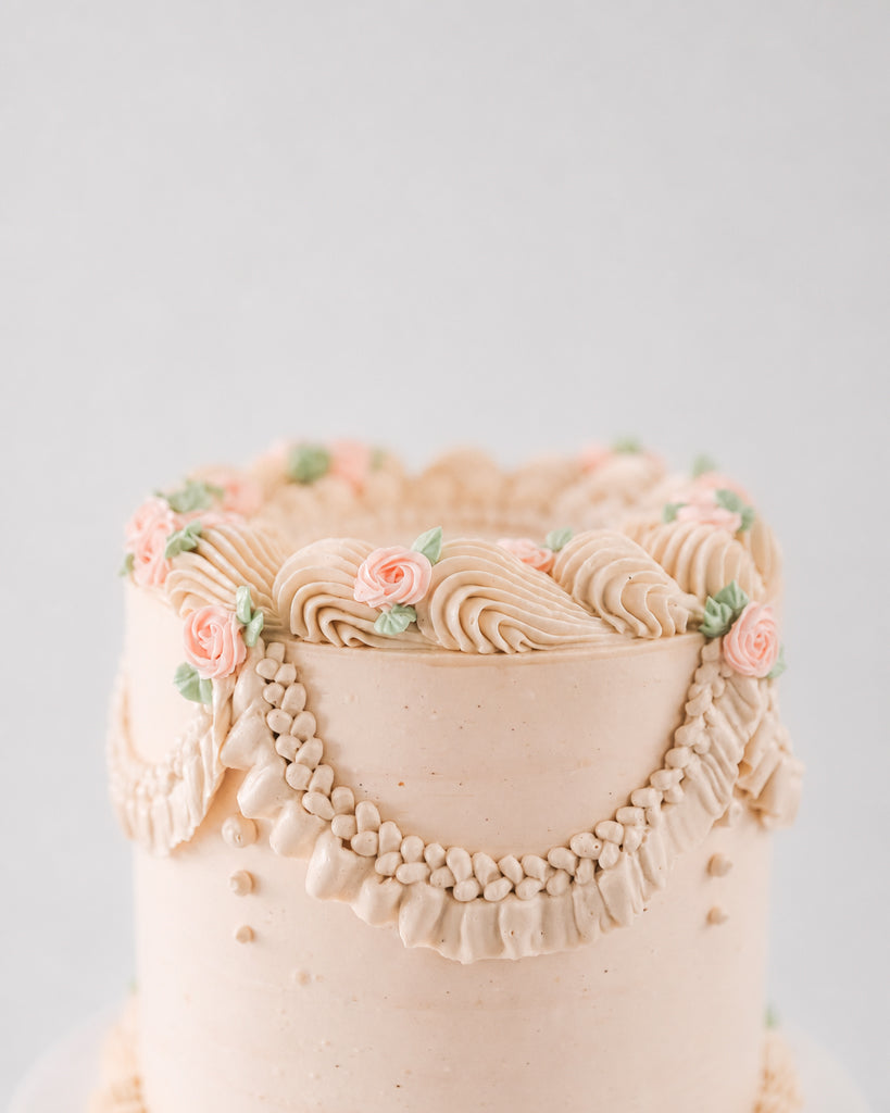 Charlotte cake detail showing ruffled scalloped border, beaded swag, and rose accents