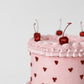 Close-up of blush pink buttercream cake with hand-piped dark red heart dot pattern