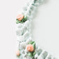 Close-up detail of Gail Marie's hand-piped mint green shell ruffle border with peach rosette blooms and sage green leaf clusters