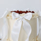 Close-up of white bow detail on buttercream cake with raspberries