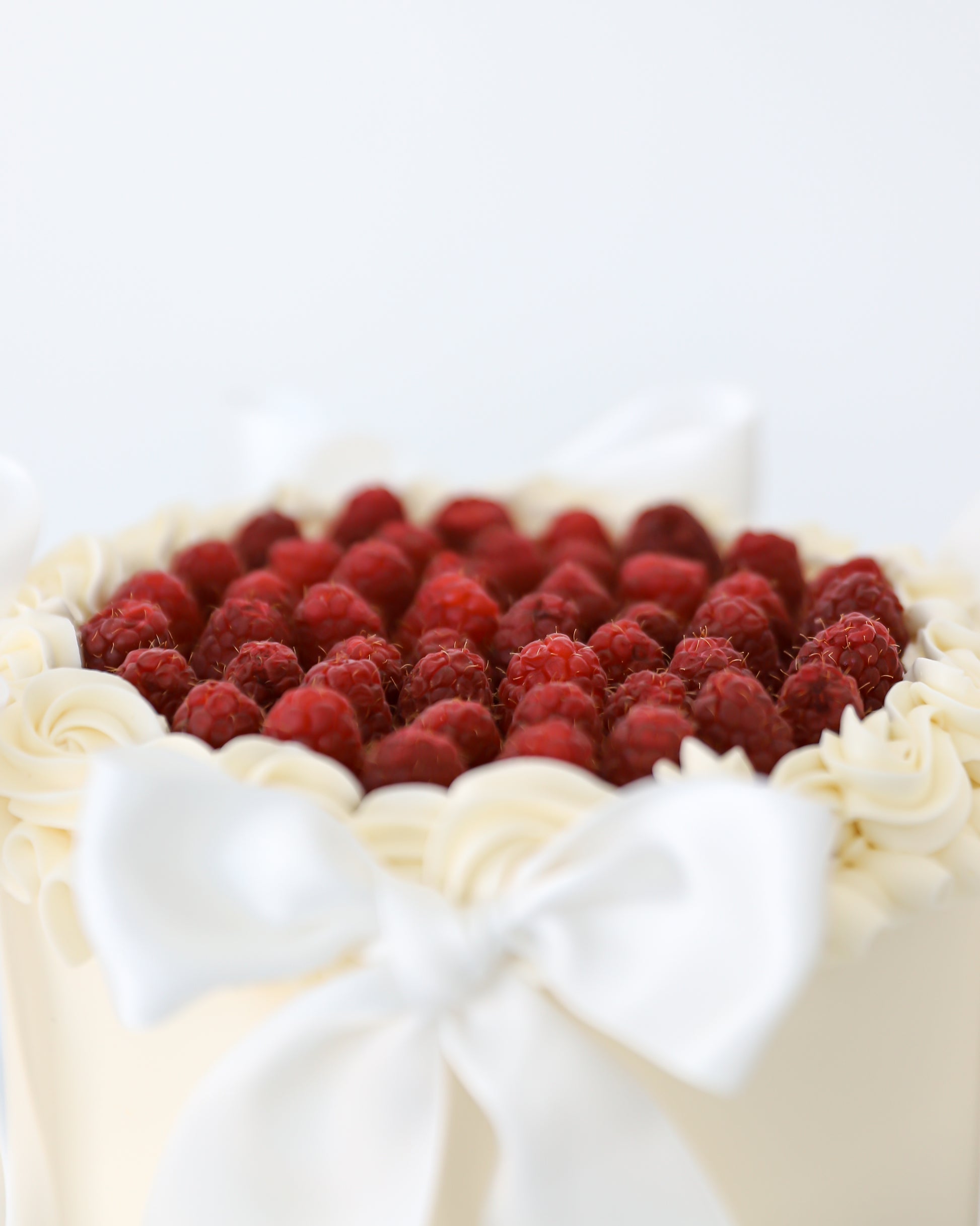 Fresh raspberry topped buttercream cake with piped vanilla border