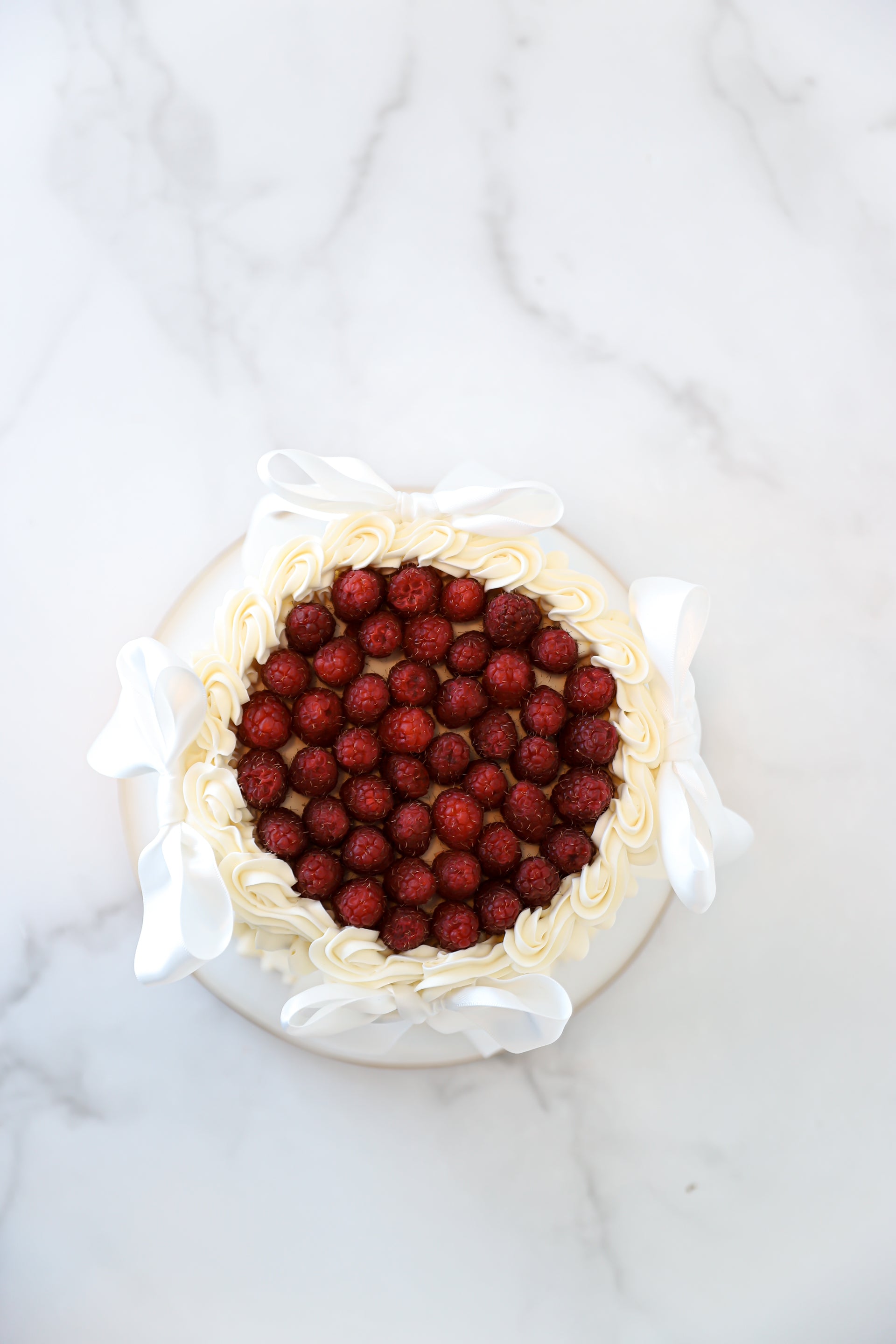 Top view of raspberry buttercream cake with white satin bows
