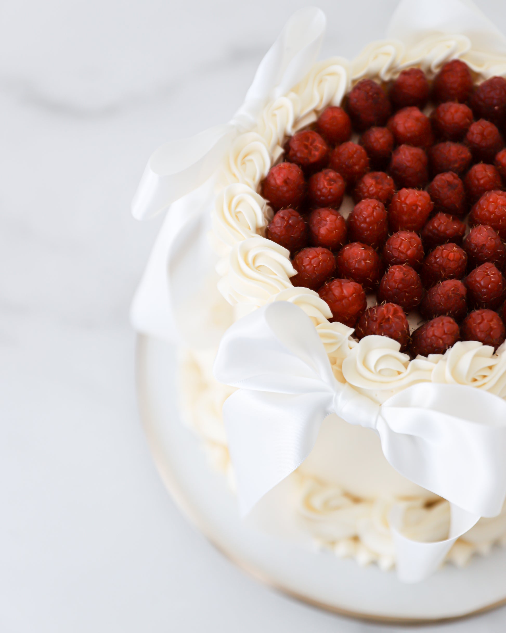 Angled top view of raspberry cake with piped buttercream and bows