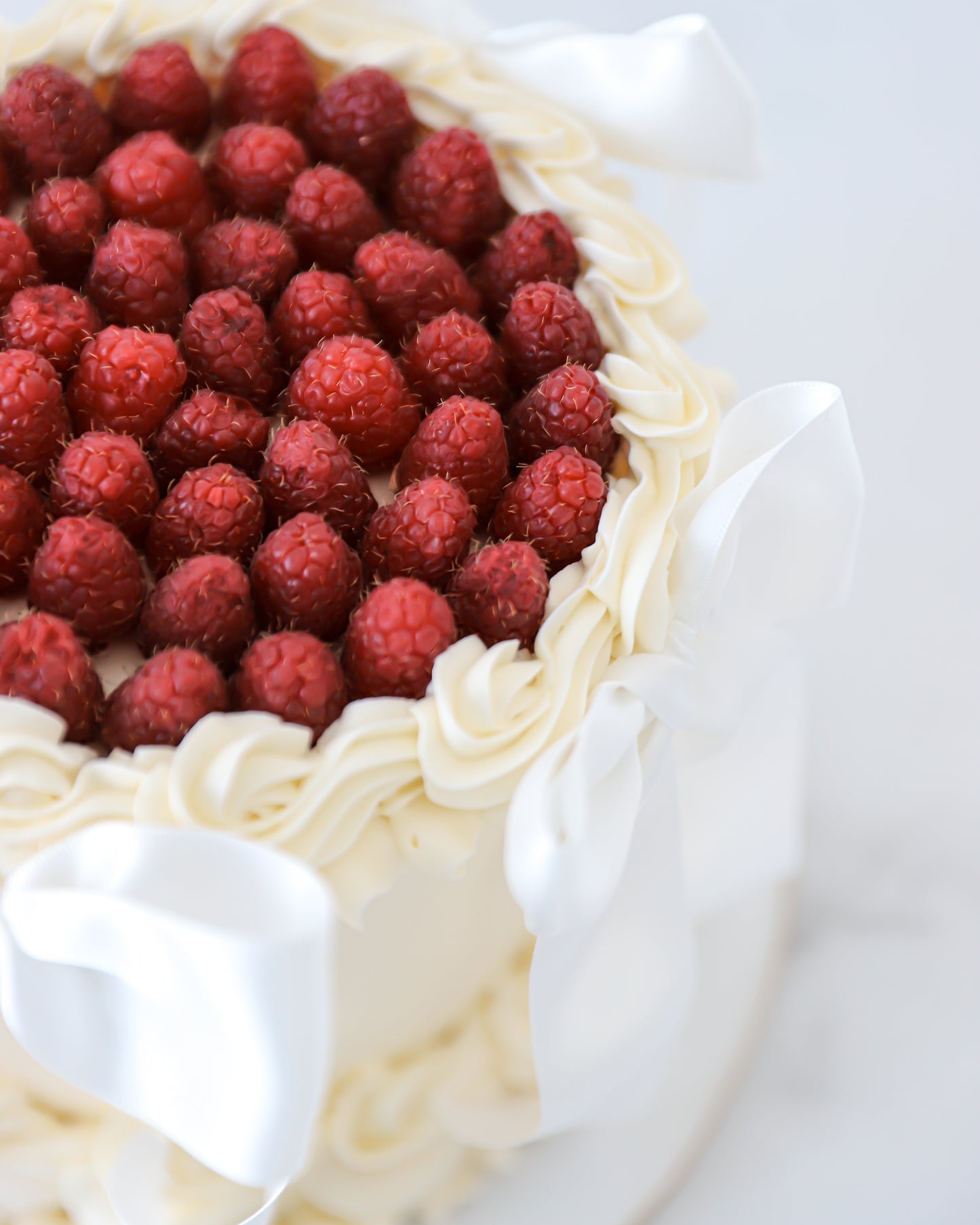 Close-up of fresh raspberries and buttercream swirl border