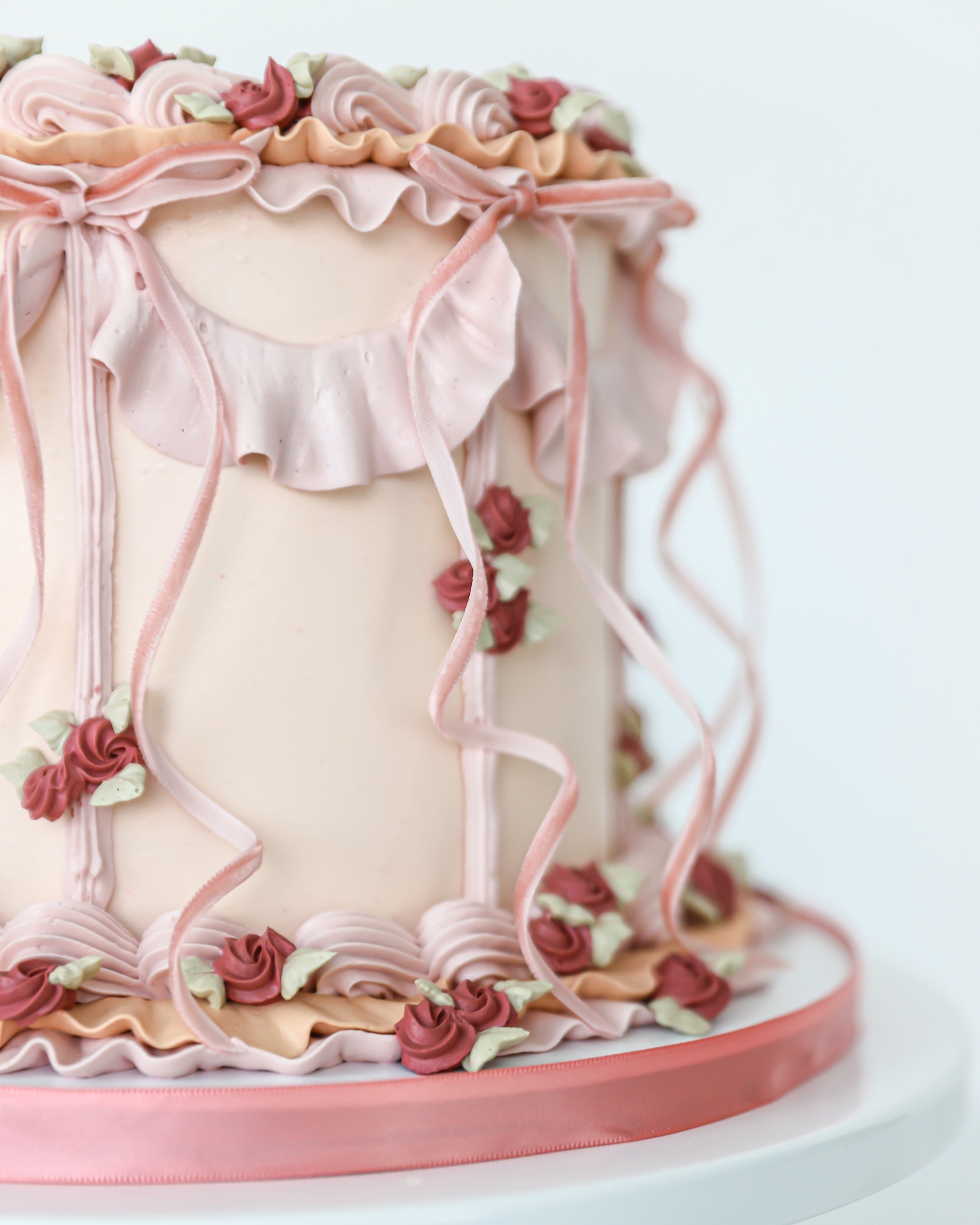 Side detail of blush buttercream cake with ribbon piping and florals