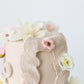 Close-up of textured buttercream detailing with delicate silk flowers
