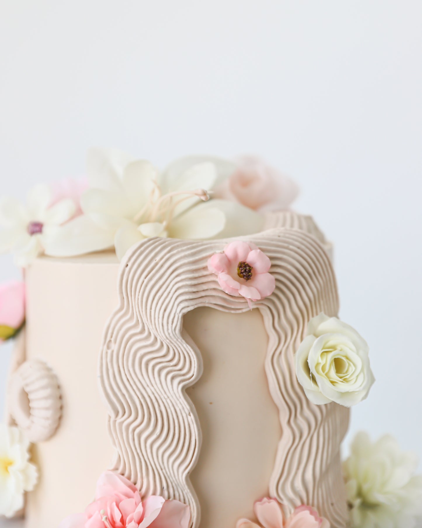 Close-up of textured buttercream detailing with delicate silk flowers