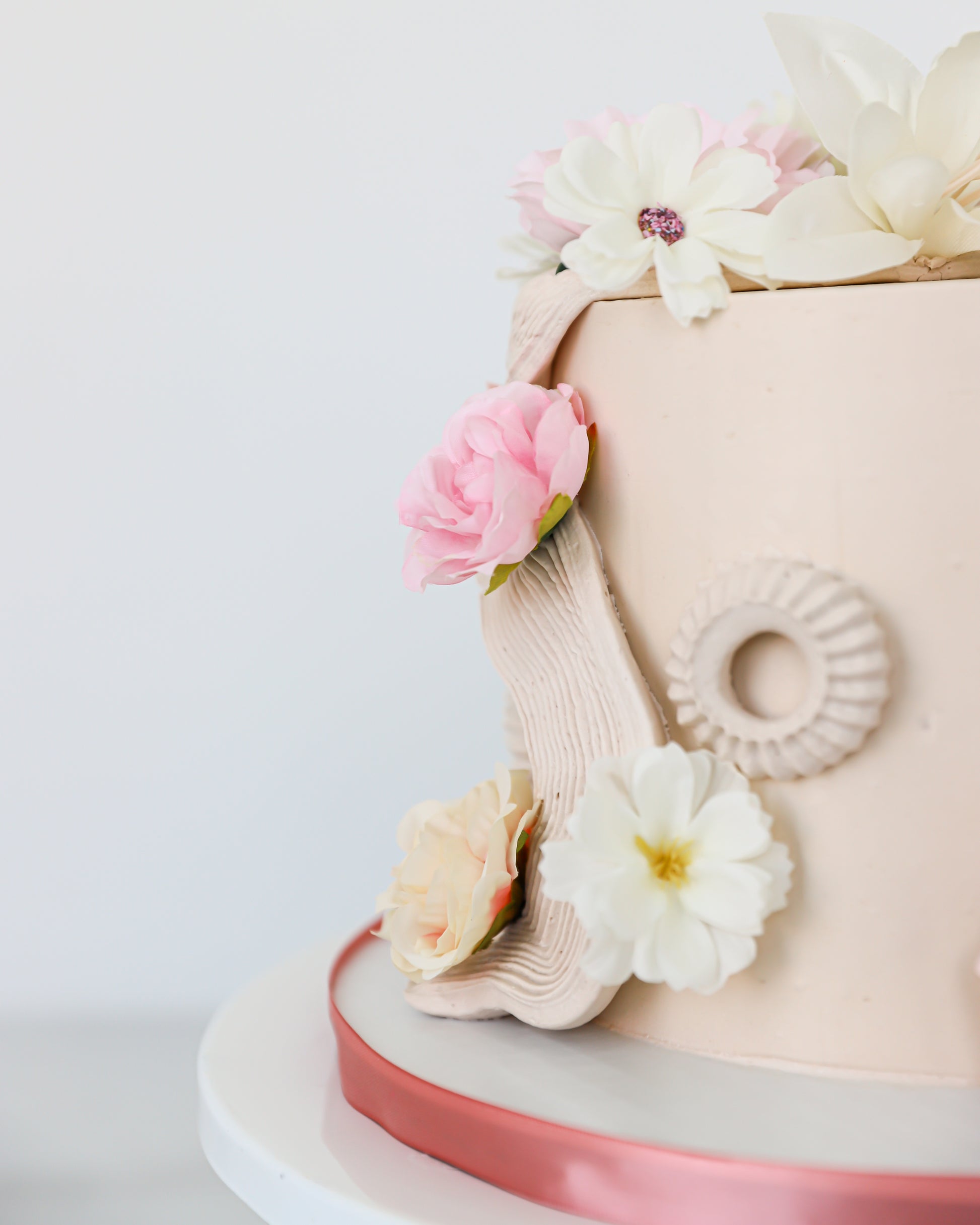 Side detail of floral buttercream cake with soft pink and ivory bloom