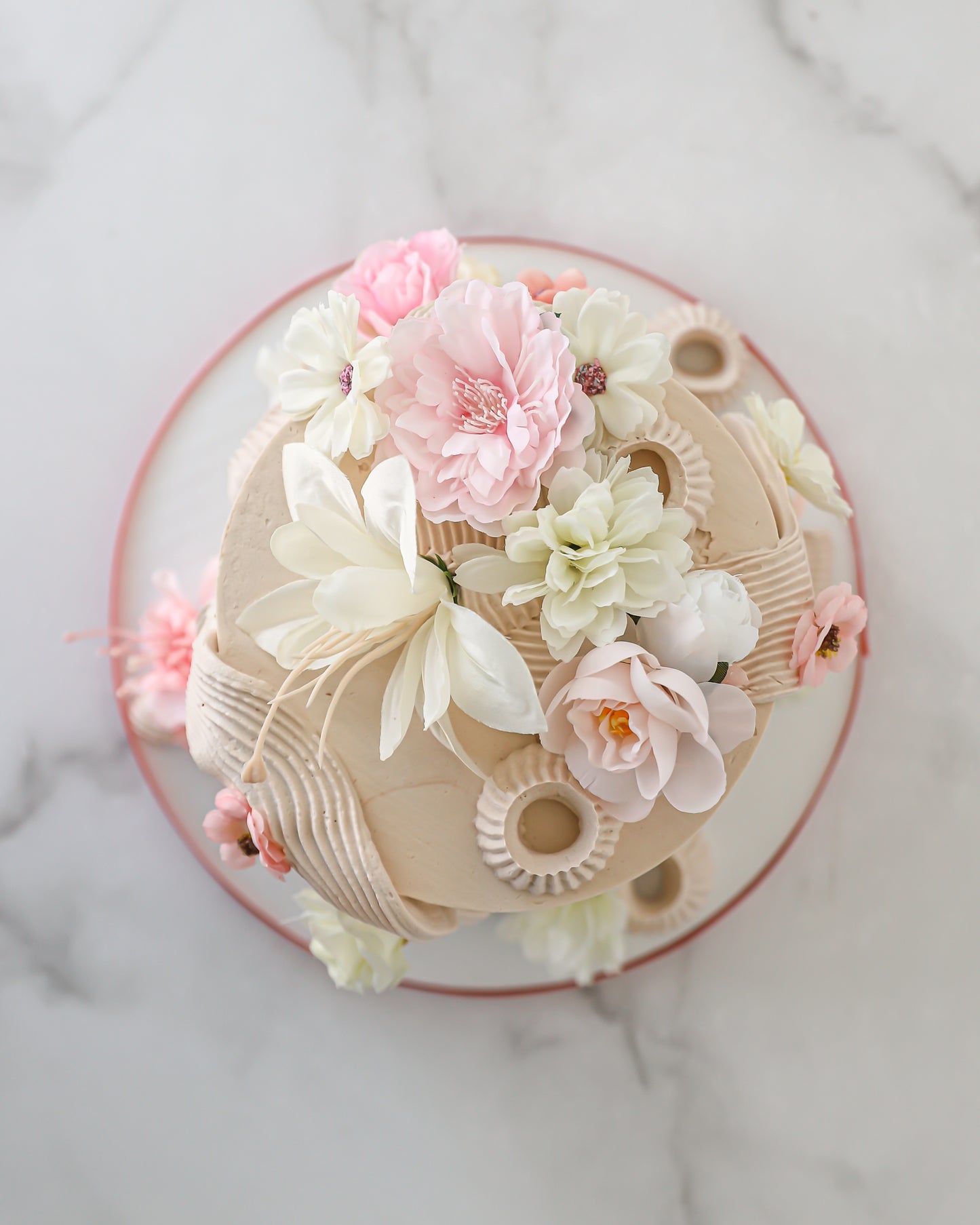 Top view of floral buttercream cake with blush and ivory silk flowers