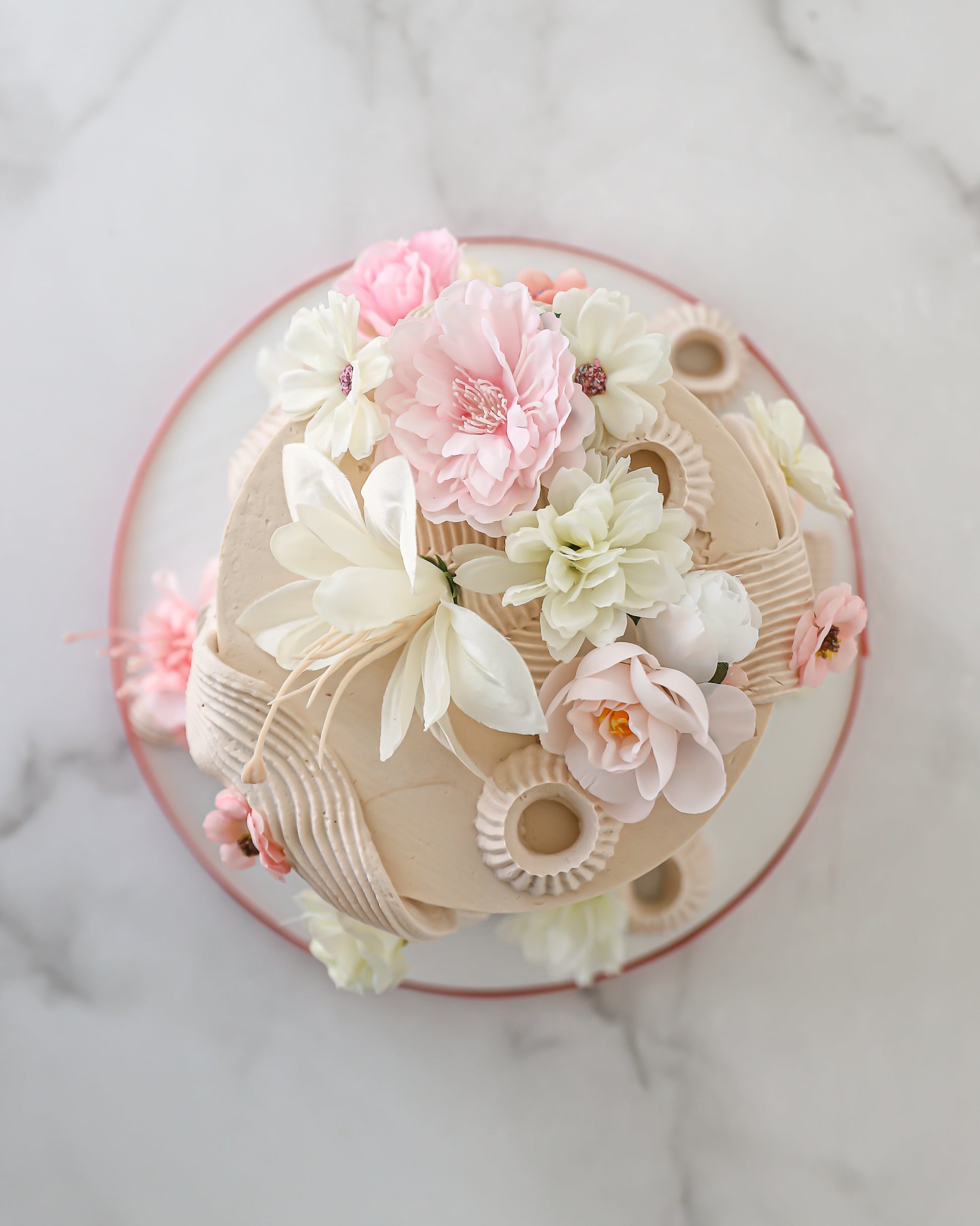 Top view of floral buttercream cake with blush and ivory silk flowers