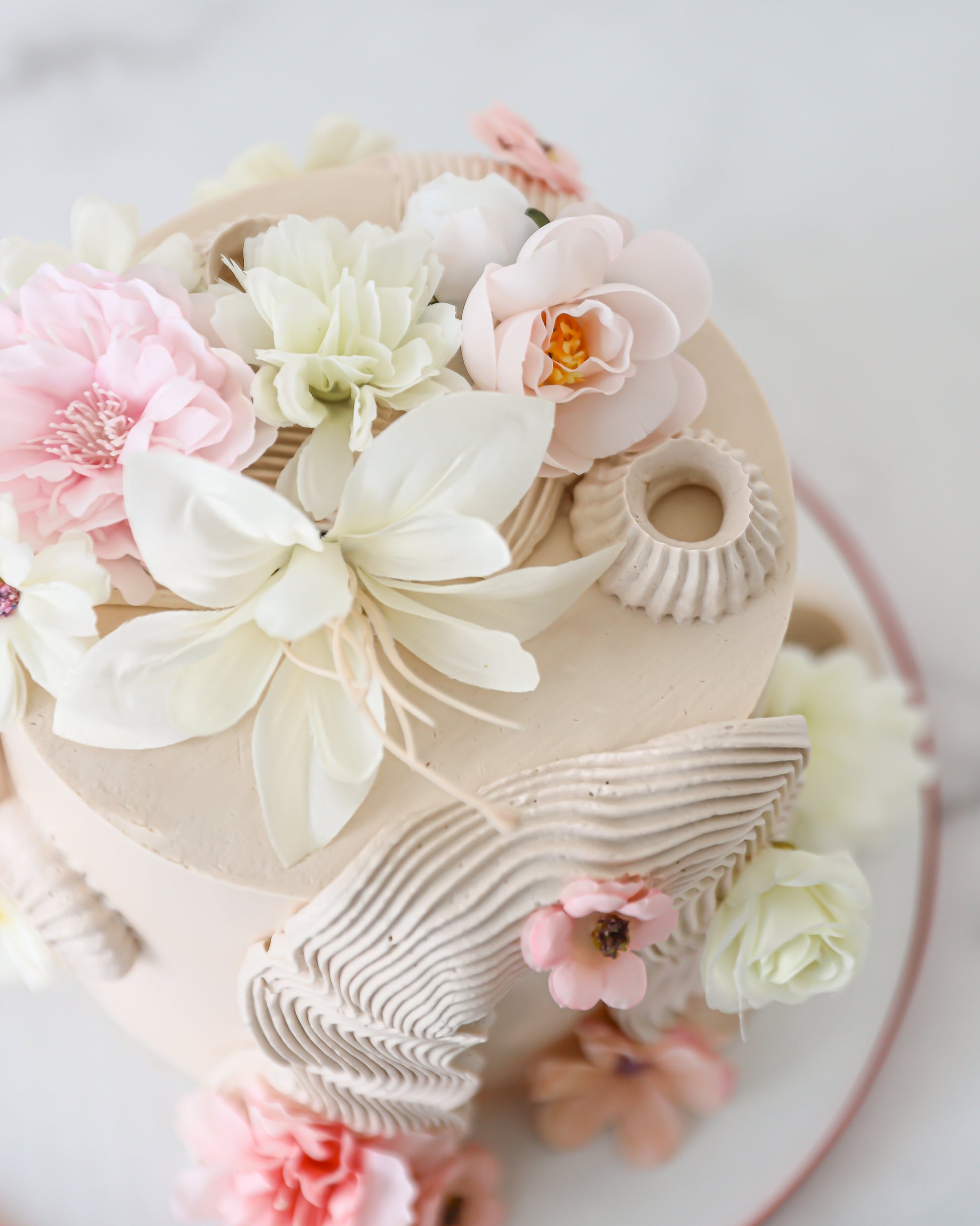 Close-up top view of soft pastel sugar flowers on buttercream cake