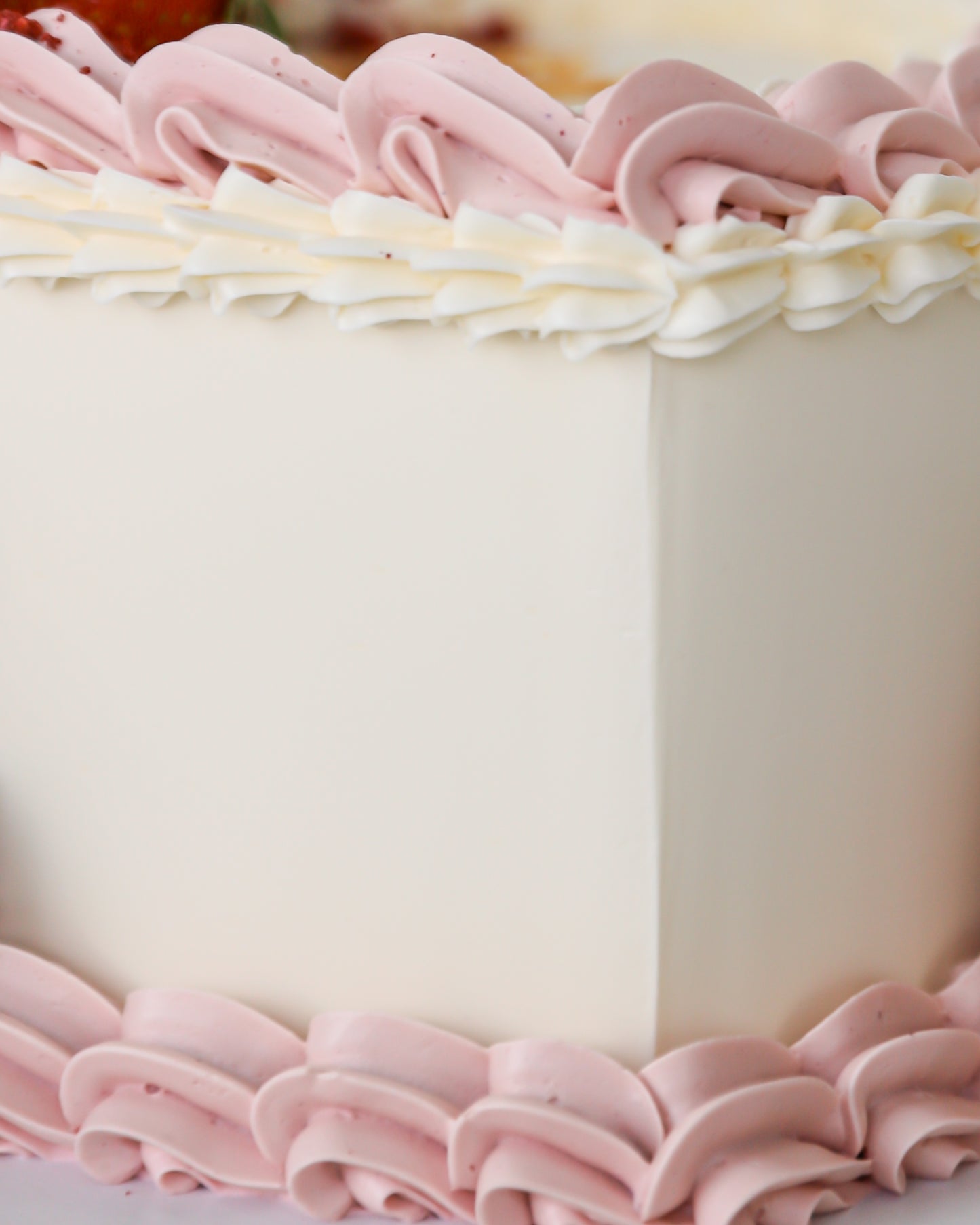 Close-up of pink buttercream piping and smooth cake finish