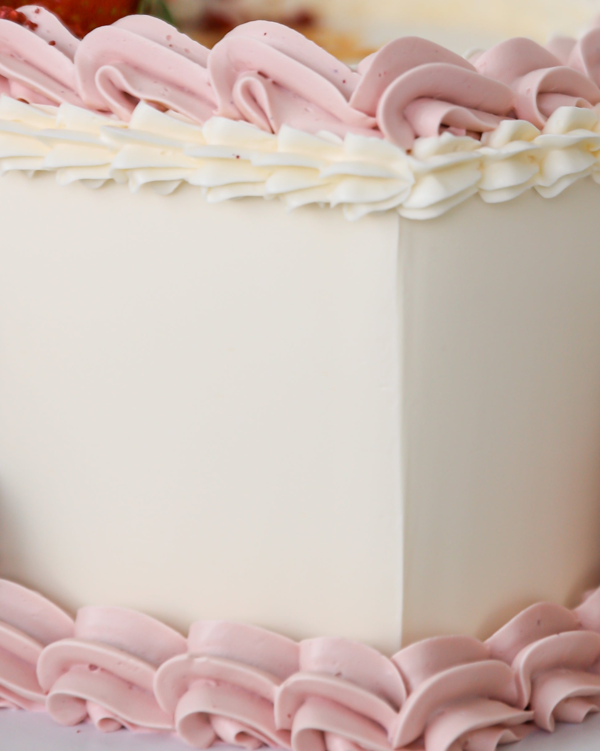 Close-up of pink buttercream piping and smooth cake finish