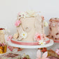 Floral Mother’s Day cake display with pastel desserts and gift boxes