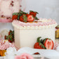 Strawberry cake display with pastel desserts and florals