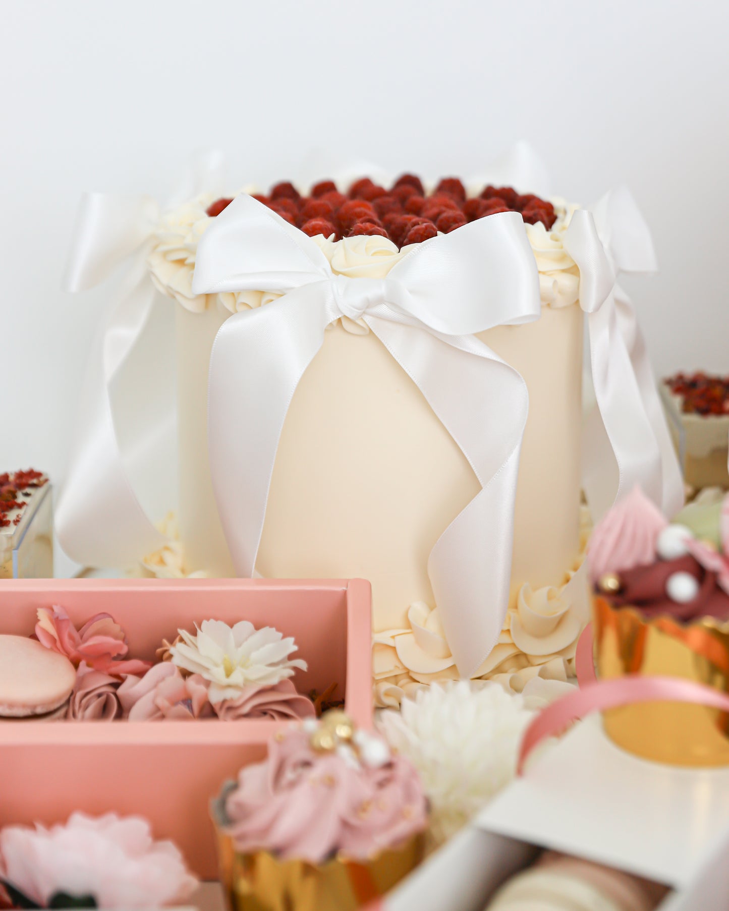 Mother’s Day cake display with bows, raspberries, and pastel desserts