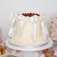 Elegant raspberry buttercream cake with white bows on display
