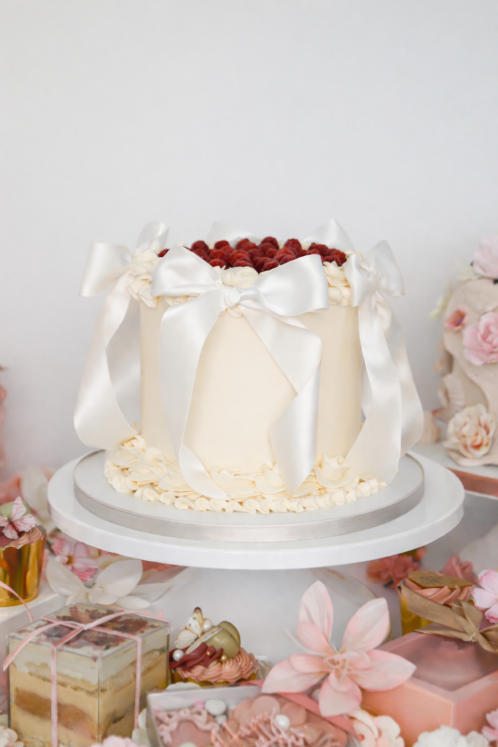 Elegant raspberry buttercream cake with white bows on display