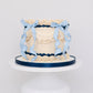 Sweetie Pie vintage lattice buttercream cake with cream ruffles, navy scalloped borders, and blue gingham ribbon on a white cake stand