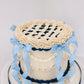 Top view of Sweetie Pie vintage lattice cake showing cream buttercream lattice top, crimped crown edge, and blue gingham ribbon