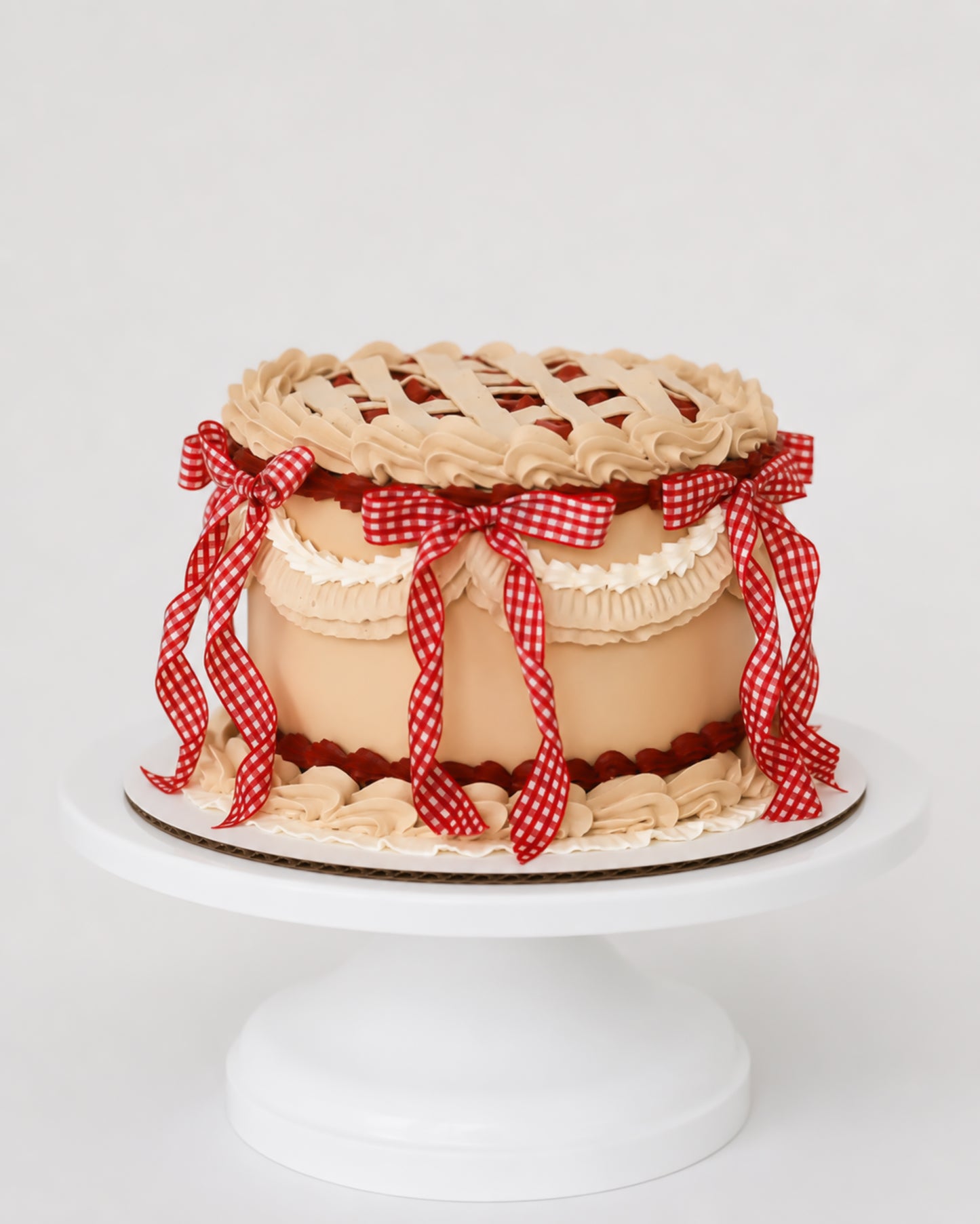 Sweetie Pie cherry vintage lattice cake with golden buttercream, red cherry filling, cream ruffle band, and red gingham ribbon cascades
