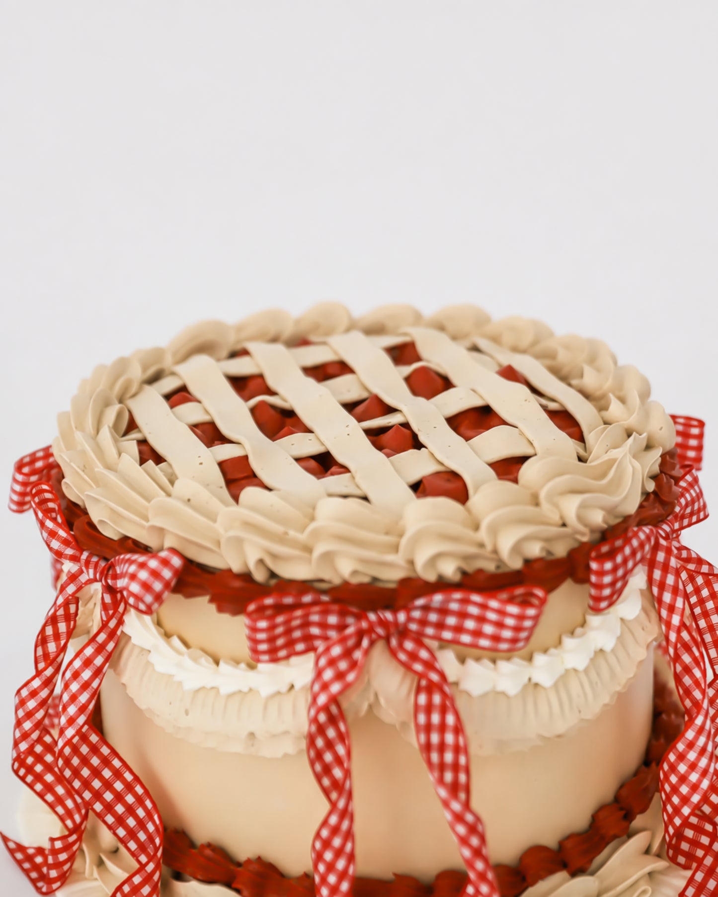 Close-up of Sweetie Pie cherry cake showing hand-piped buttercream lattice top and crimped crown edge with red cherry filling