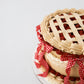 Angled view of Sweetie Pie cherry vintage lattice cake with red gingham ribbon bows and golden buttercream ruffles